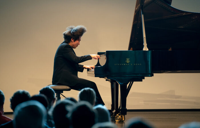 Pianisti Seong-Jin Cho esiintymässä Mäntän Musiikkijuhlilla. Pianisti näyttää soittavan vauhdikkaasti ja keskittyneesti, hänen hiuksensa ovat pysähtyneet ilmavirran mukana kuvanottohetkellä pystyyn.