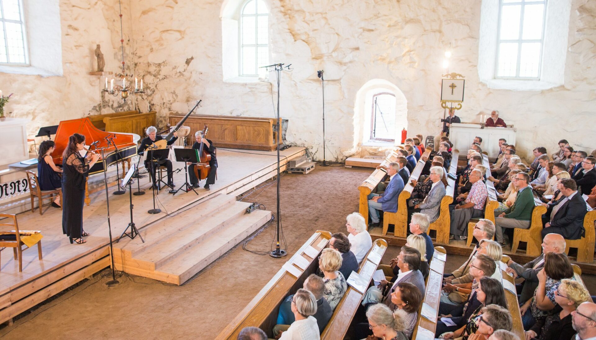 Ihmisiä kuuntelemassa konserttia vanhassa kivikirkossa