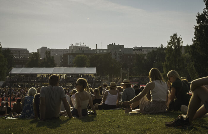 People sitting on grass at an open air festival