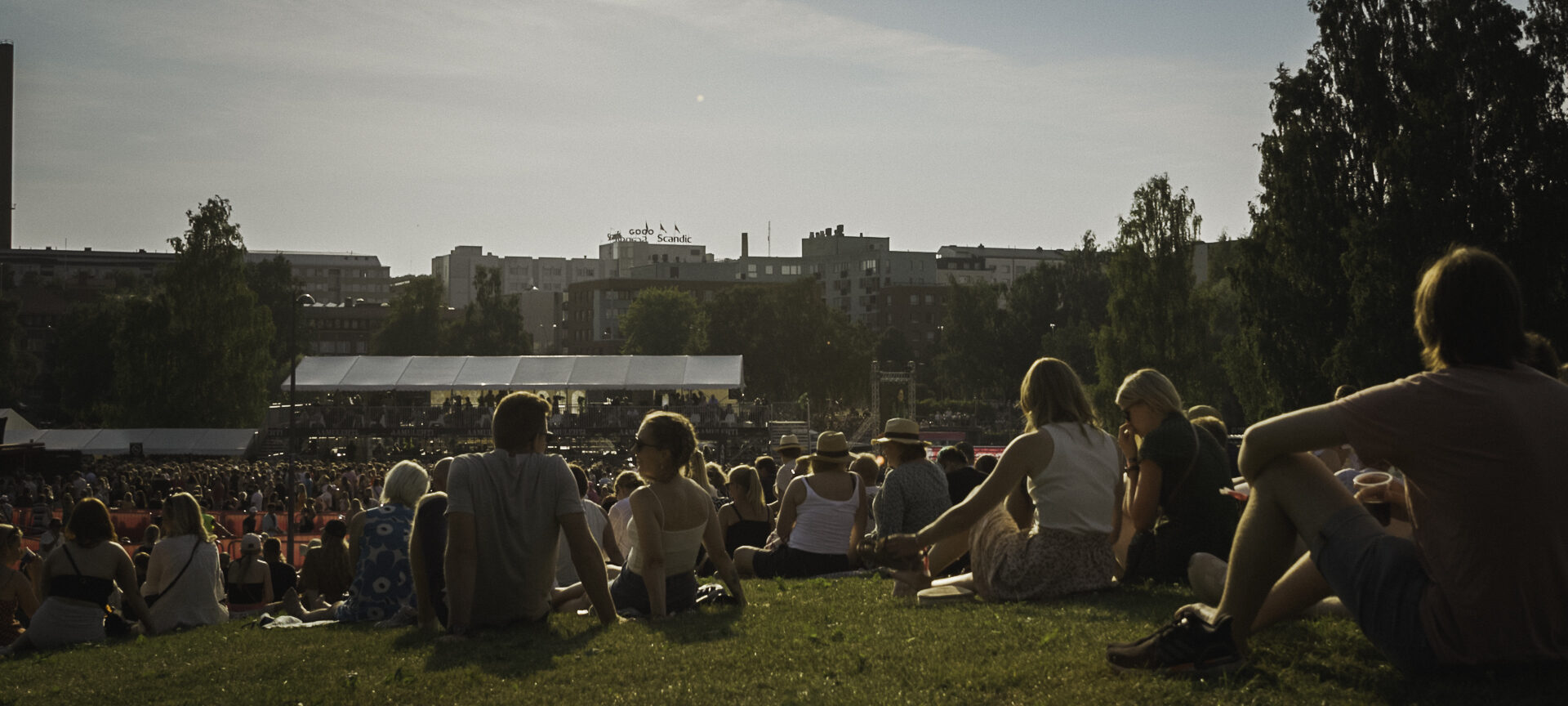 People sitting on grass at an open air festival