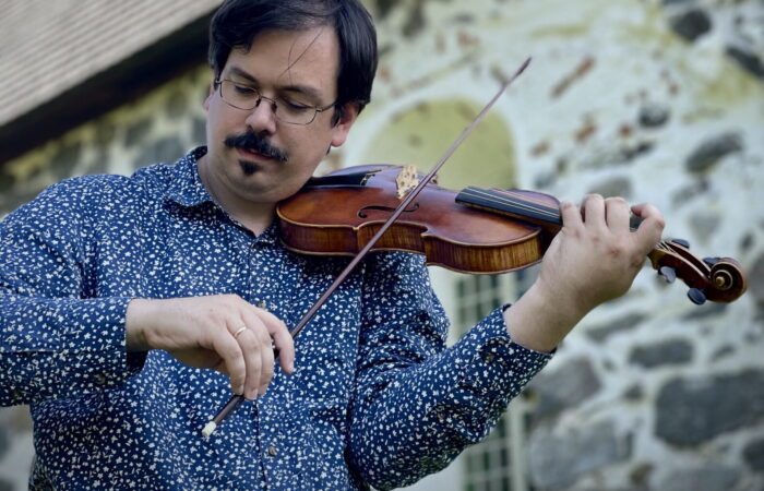Anthony Marini soittaa viulua vanhan kirkkorakennuksen edessä.