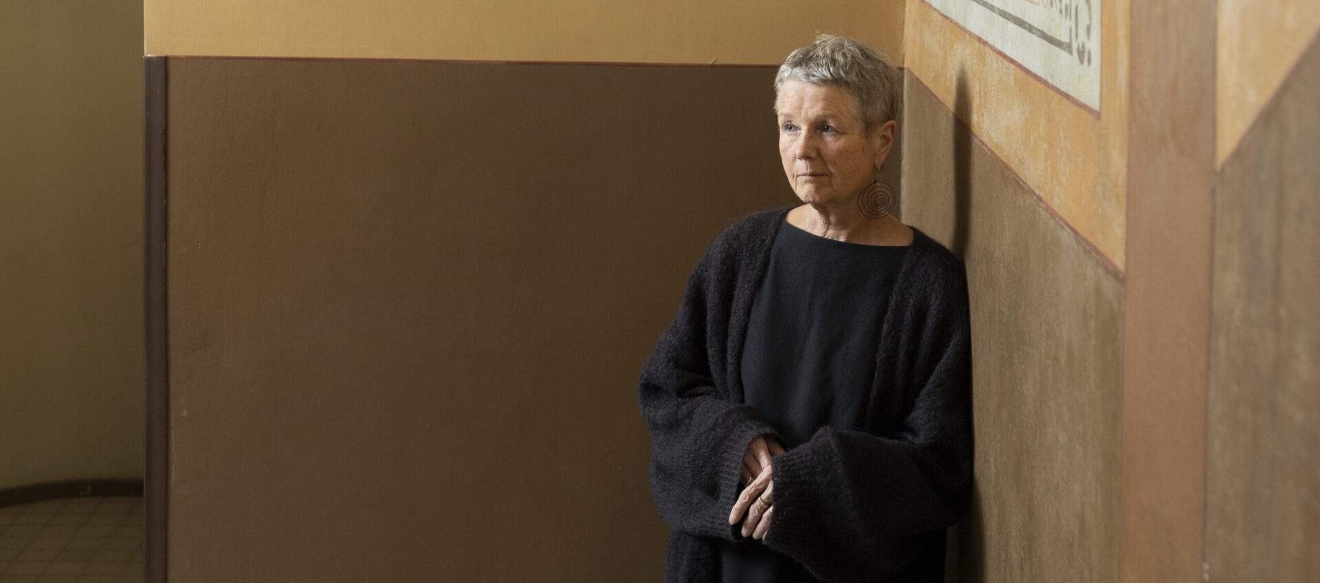 Leena Kumola nojaa kiviseinään.