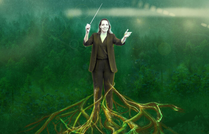 Kuvassa naiskapellimestari, taustalla metsämaisema. Kapellimestarin jalat yhdistyvät puun juurakkoon. Kapellimestarin kädessä on tahtipuikko.