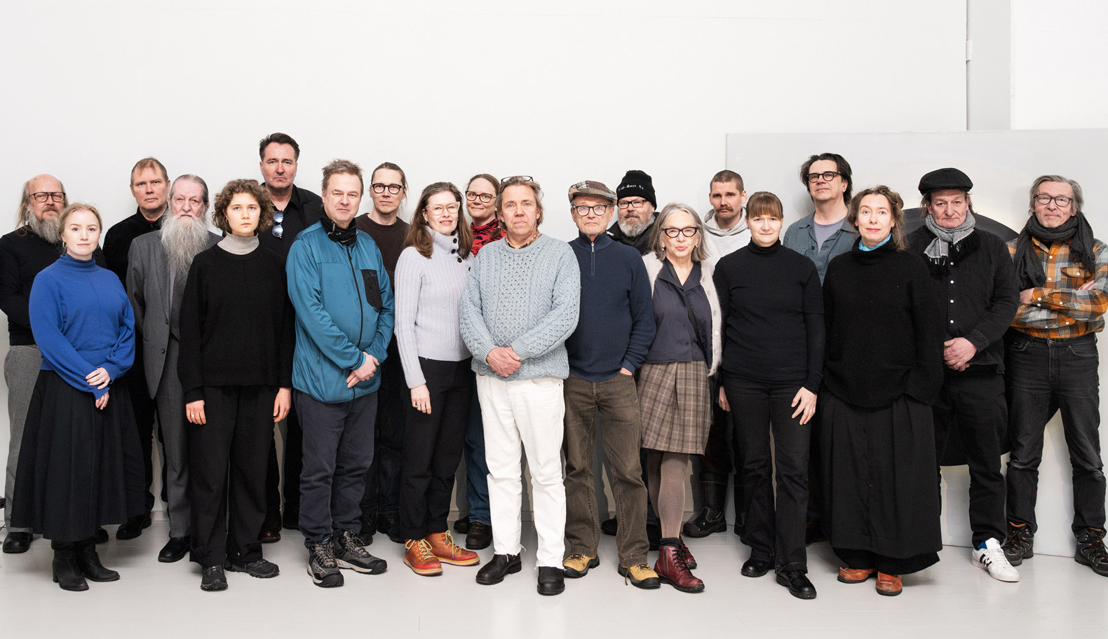 Ryhmävalokuva Mäntän kuvataideviikkojen taiteilijoista. Valokuvassa 20 henkilöä kahdessa rivissä valkoista taustaa vasten.